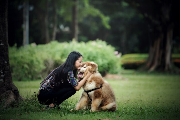 屋外の公園で彼女の小さな犬と遊ぶ美しい若い女性。ライフスタイルの肖像画。