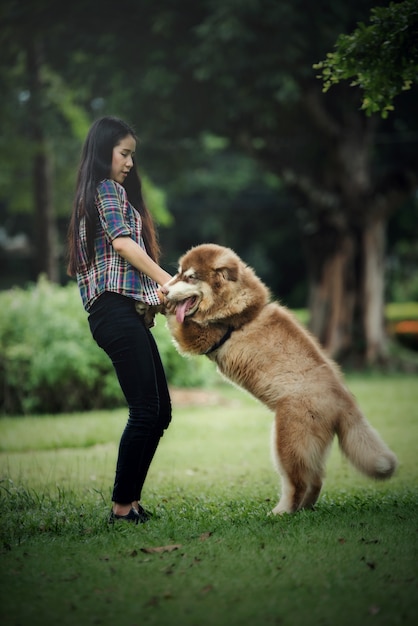 屋外の公園で彼女の小さな犬と遊ぶ美しい若い女性。ライフスタイルの肖像画。