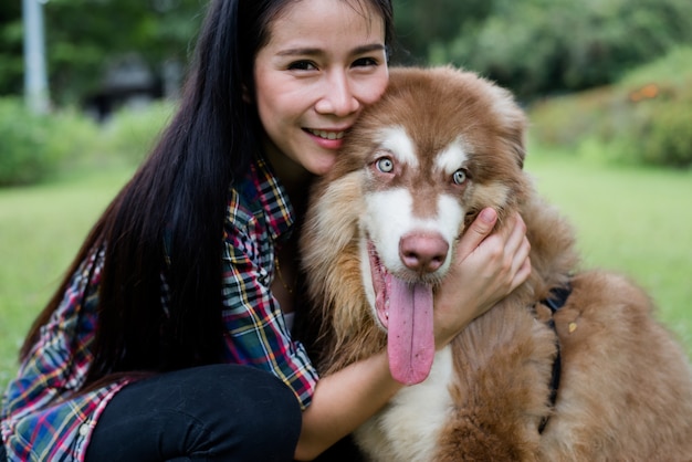 屋外の公園で彼女の小さな犬と遊ぶ美しい若い女性。ライフスタイルの肖像画。