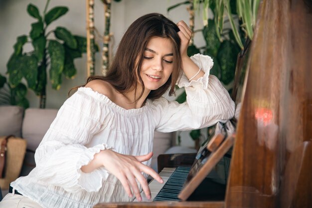 A beautiful young woman plays the old wooden piano