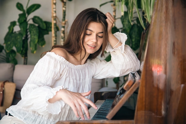 A beautiful young woman plays the old wooden piano