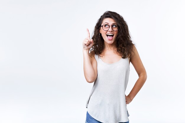 Beautiful young woman pointing up over white background.