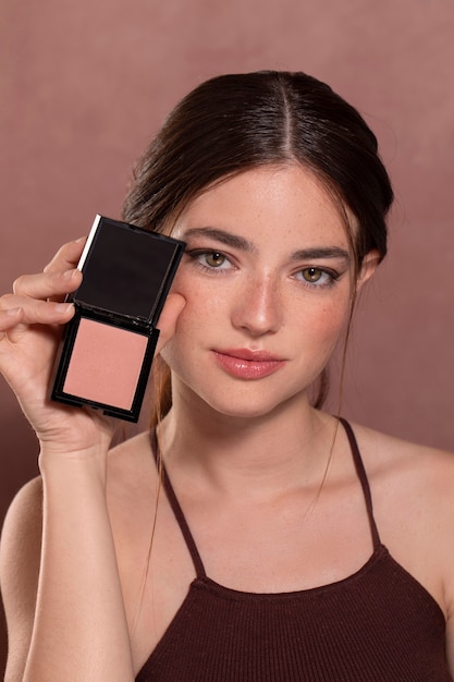 Портрет красивой молодой женщины с продуктом макияжа