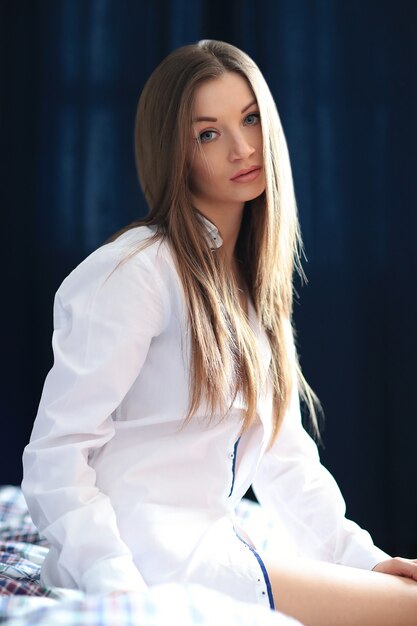 Beautiful young woman posing with male shirt in the bed