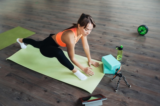 Bella giovane donna che pratica yoga, è impegnata con l'insegnante online tramite un tablet. concetto di sport domestico.