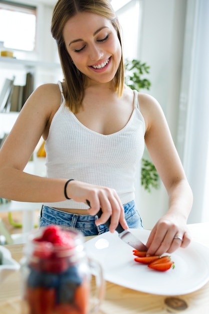 Bella giovane donna che prepara la colazione a casa.