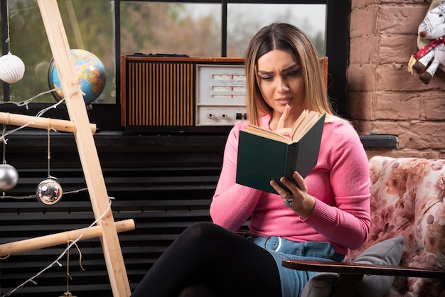 Foto gratuita bella giovane donna che legge un libro a casa