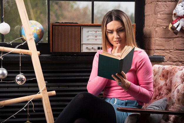 Beautiful young woman reading book at home