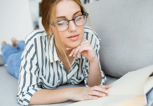 Beautiful young woman reading a book at home.