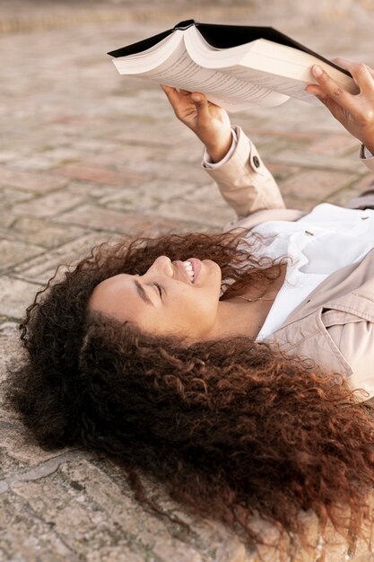 Beautiful young woman reading a book outside