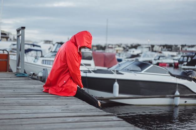 Free photo beautiful young woman in a red cloak in the yacht port. stockholm, sweden