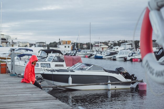 Beautiful young woman in a red cloak in the yacht port. Stockholm, Sweden