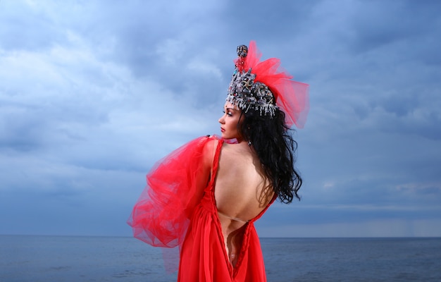 Free photo beautiful young woman in red long dress near the sea