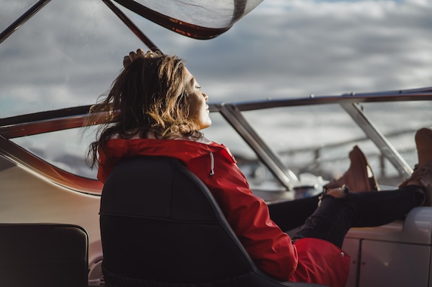 Foto gratuita bella giovane donna in un impermeabile rosso cavalca uno yacht privato. stoccolma, svezia