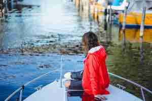 Foto gratuita bella giovane donna in un impermeabile rosso cavalca uno yacht privato. stoccolma, svezia