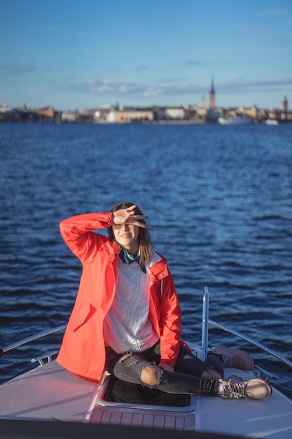 Beautiful young woman in a red raincoat rides a private yacht. stockholm, sweden