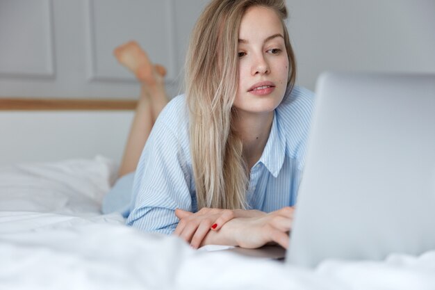 노트북으로 침대에서 편안한 아름 다운 젊은 여자