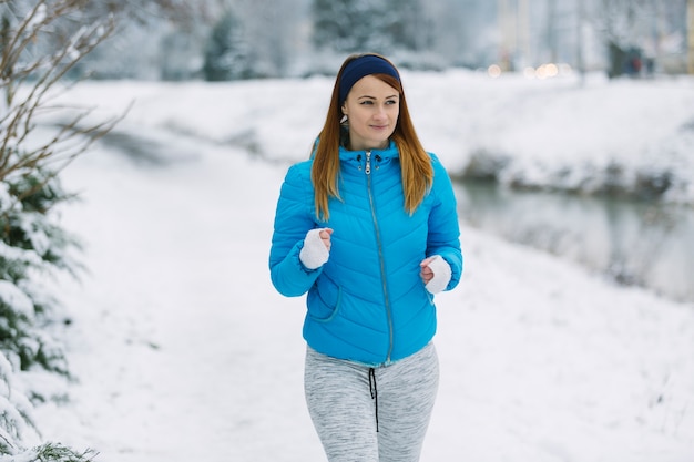 Beautiful young woman running on snowy landscape