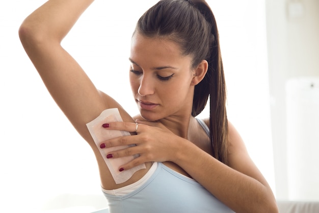 Free photo beautiful young woman shaving her armpit with wax in the bathroom.