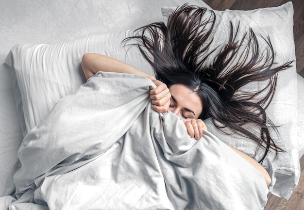 A beautiful young woman sleeps in a white bed