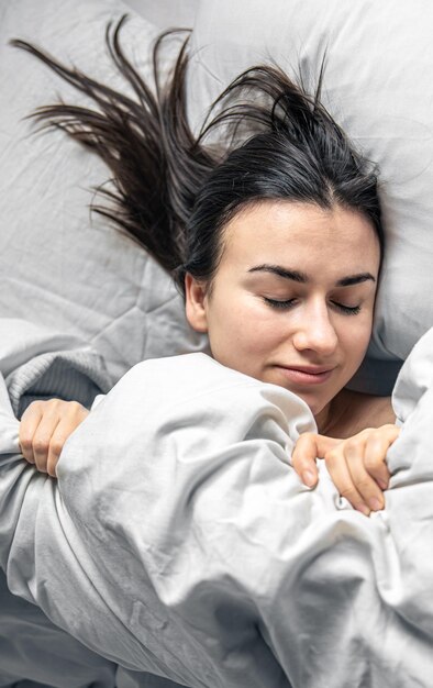 A beautiful young woman sleeps in a white bed