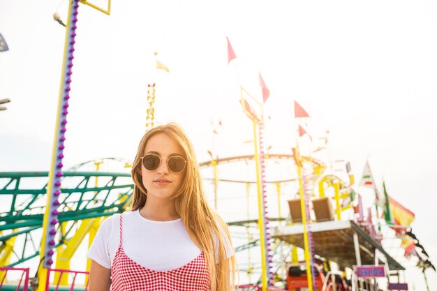 Beautiful young woman standing in front of roller coaster
