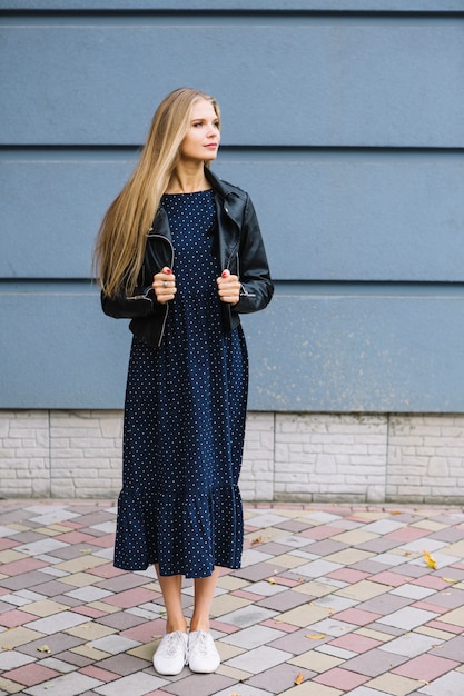 Free photo beautiful young woman standing in front of wall holding wore jacket