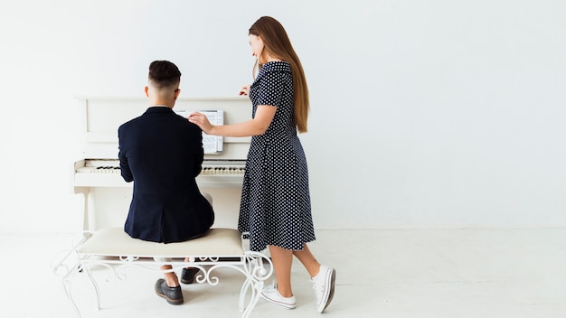 Красивая молодая женщина, стоя возле человека, играя на пианино