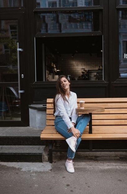 Beautiful young woman in street cafe drinks coffee