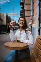 Free photo beautiful young woman in street cafe drinks coffee