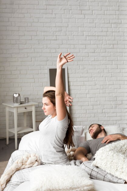 Beautiful young woman stretching in bed