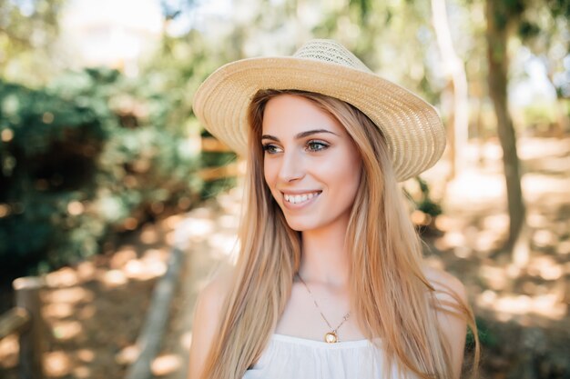 Beautiful young woman in summer hat walking in the city.