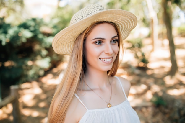 Beautiful young woman in summer hat walking in the city.