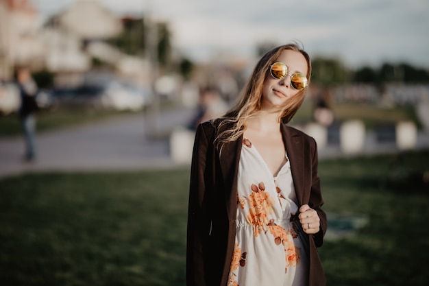 Beautiful young woman in sunglasses in the city at sunset