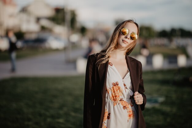 Beautiful young woman in sunglasses in the city at sunset