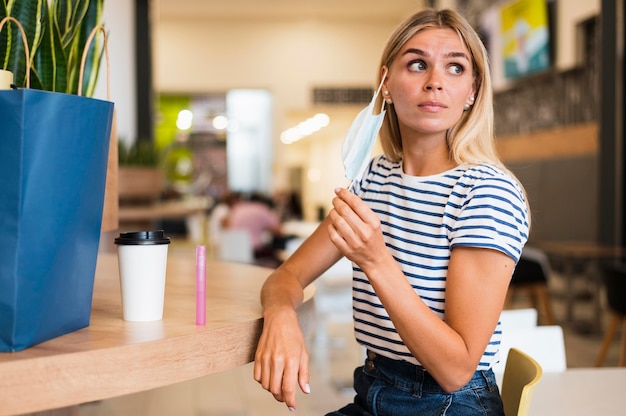 Foto gratuita bella giovane donna che toglie la maschera per il viso