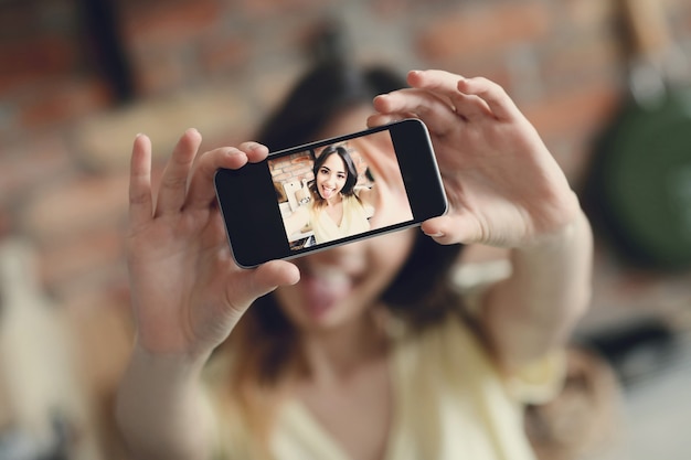 Beautiful young woman taking selfie with smartphone