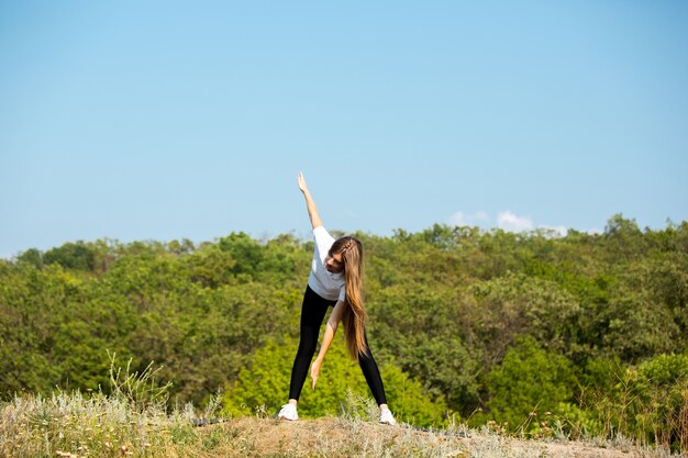 Beautiful young woman training flexibility outdoors