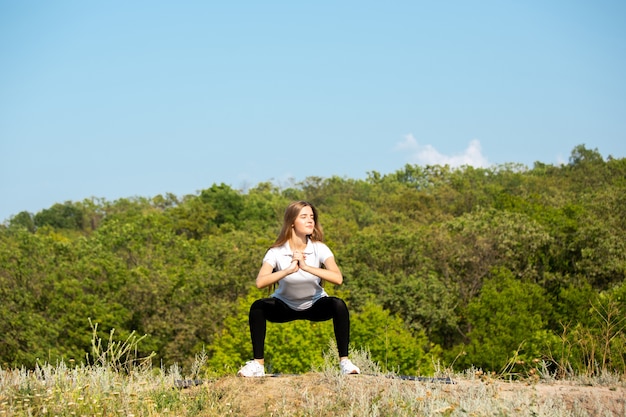 Beautiful young woman training flexibility outdoors