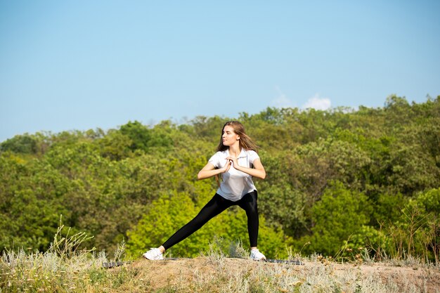 Beautiful young woman training flexibility outdoors