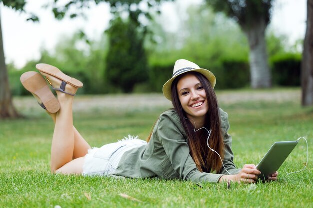 公園でデジタルタブレットを使用している美しい若い女性。