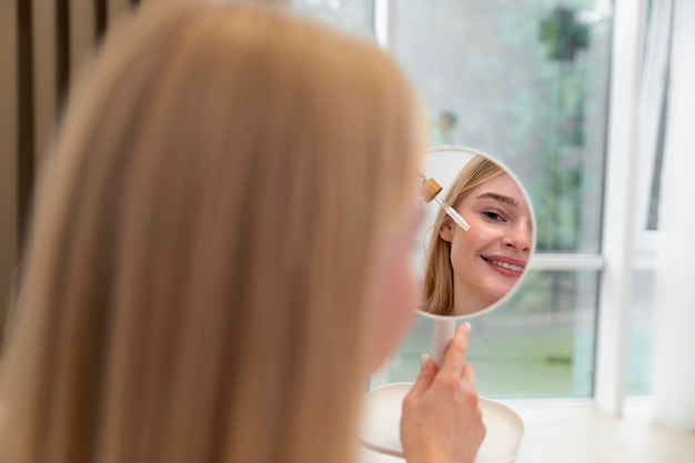 Beautiful young woman using a face care oil