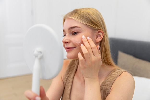 Beautiful young woman using a face care product