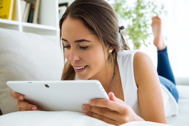 Beautiful young woman using her digital tablet at home.