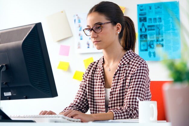 Beautiful young woman using her laptop in the office.