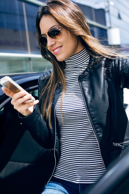아름 다운 젊은 여자는 차에 그녀의 휴대 전화를 사용 하여.