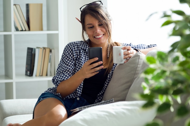 Free photo beautiful young woman using her mobile phone at home.