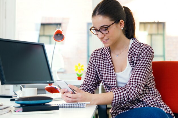 Beautiful young woman using her mobile phone in the office