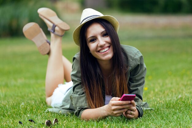 공원에서 그녀의 휴대 전화를 사용하여 아름다운 젊은 여자.