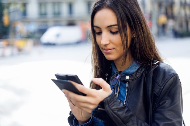 Beautiful young woman using her mobile phone in the street.